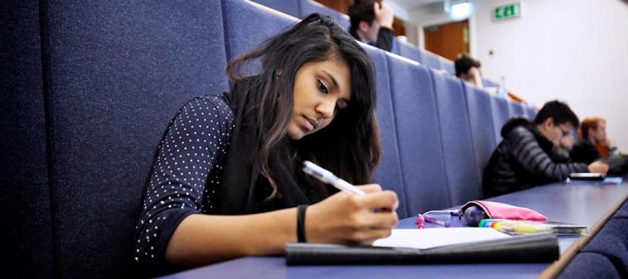 Student sitting writing in modern lecture theatre